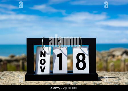 Nov 18 Kalenderdatumstext auf Holzrahmen mit verschwommenem Hintergrund des Ozeans. Kalenderdatum Konzept. Stockfoto