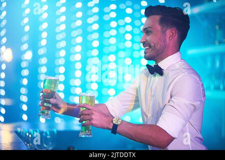 Erstklassige Barkeeper. Ein fröhlicher Barkeeper serviert zwei Gläser Bier an einer Bar. Stockfoto