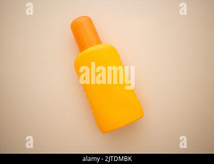Orangefarbene Plastikflasche vor sandfarbenem Hintergrund Stockfoto