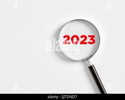 Die Lupe vergrößert das Jahr 2023 auf weißem Hintergrund. Fokus auf das Jahr 2023 für das Business Planning Konzept. Stockfoto