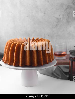 Rum-gebundener Kuchen auf einem weißen Kuchenständer, eingeweicht gebundener Kuchen, goldener Kuchen Stockfoto