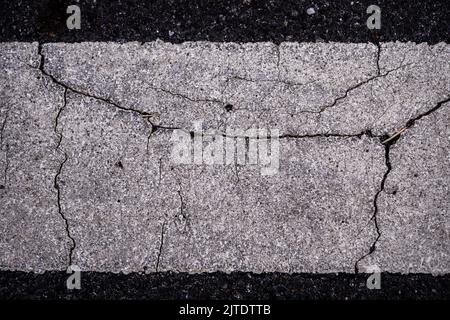 Nahaufnahme der Risse auf der Oberfläche von Road Line lackiert Stockfoto