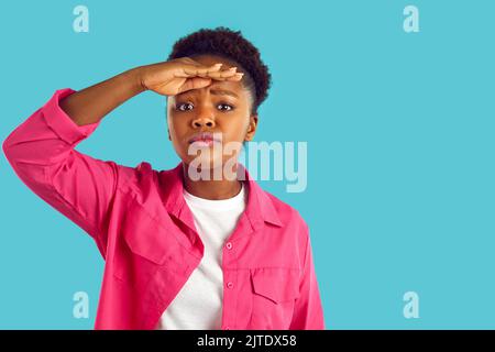 Frau, die die Hand über die Augen hält und in die Ferne blickt und jemanden am Horizont erwartet und sucht. Stockfoto