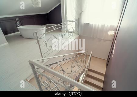 Weißes Badezimmer und Treppe im modernen, zeitgenössischen Innenbereich des Hauses. Stockfoto