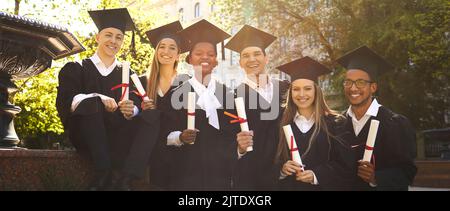 Freudige Gruppe multirassischer Studenten, die zusammen das Diplom der Graduierung und der Ausbildung erhielten. Stockfoto