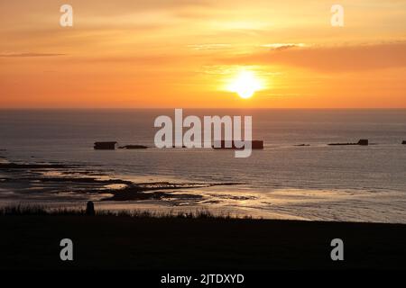 Sonnenuntergang über den Überresten des Mulberry Harbour von WW2 am Gold Beach, Arromanches-les-Bains, Normandie, Frankreich. Stockfoto