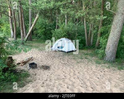 Das Zelt steht im Wald neben dem Grill Stockfoto