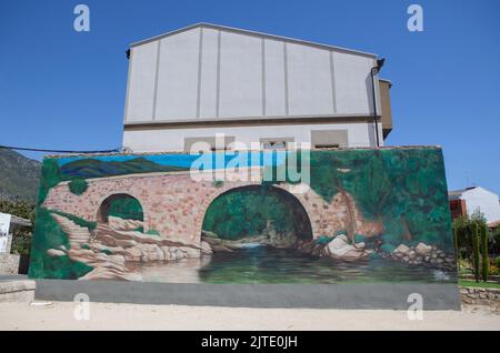 Losar, Spanien - 23.. August 2022: Graffiti verzierte Wand mit Darstellung der Cuartos-Brücke in Losar de la Vera, Caceres, Extremadura, Spanien Stockfoto