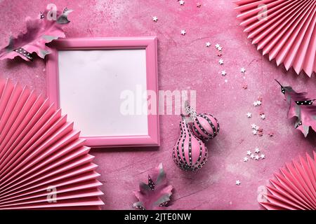 Rosafarbener Bilderrahmen mit gestreifte Kürbisse aus dem Herbst, herbstlich trockene Blätter. Papierfächer, Zucker streut auf rosa strukturiertem monochromatischem Hintergrund. Stockfoto