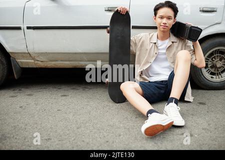 Teenager mit Skateboard und tragbaren Lautsprechern im Freien Stockfoto