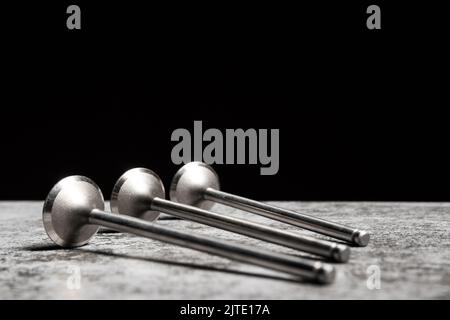 Auf schwarzem Hintergrund liegen die Motorventile des Autos auf dem Tisch Stockfoto