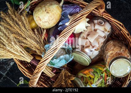 Weidenkorb mit Pasta in Gläsern, Kürbis und einem Bouquet von getrocknetem Weizen. Vegetarisches Set aus dem Laden Stockfoto