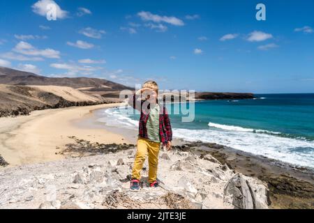 Kleiner Junge, der die Strandlandschaft namens Caleta del Congrio im Nationalpark Los Ajaches auf Lanzarote, Kanarische Inseln, Spanien, genießt Stockfoto