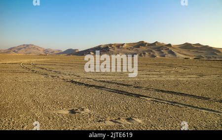 Spuren von Autoreifen in der Wüste. Abendliche Landschaften des Paracas National Reserve Park, Peru Stockfoto