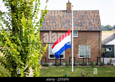 NEW BEIJERLAND - Dänemark, 2022-08-30 10:44:46 Klaaswaal - Eine Fahne an einem Haus im Hoeksche Waard hängt am halben Mast, um an die Opfer des tödlichen Unfalls zu erinnern. Am Samstag fuhr ein LKW vom Deich in Nieuw-Beijerland und traf die Anwesenden bei einer Nachbarschaftsfeier. Zusätzlich zu den sieben Verletzten wurden sechs Menschen getötet. ANP JEFFREY GROENEWEG niederlande Out - belgien Out Stockfoto