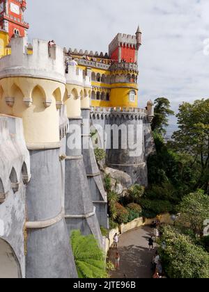 Außenansicht des Pena-Palastes mit Touristen, die auf der Straße unten zu Fuß gehen, Sintra, Stadtteil Lissabon, Portugal. Stockfoto