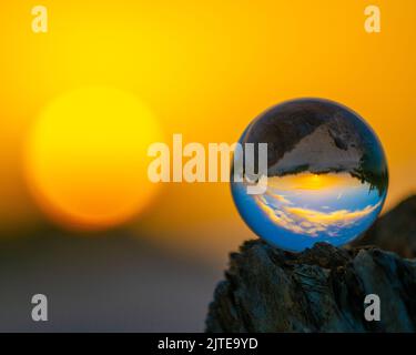 Nahaufnahme einer Kristallkugel mit Bergreflexionen bei Sonnenuntergang Stockfoto