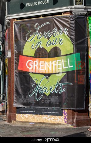 Grenfell-Unterstützungsbanner beim Notting Hill Carnival am Montag, den 2022. August, an den Bankfeiertagen in London, Großbritannien. Grenfell, für immer in unseren Herzen. Geschlossener Pub Stockfoto