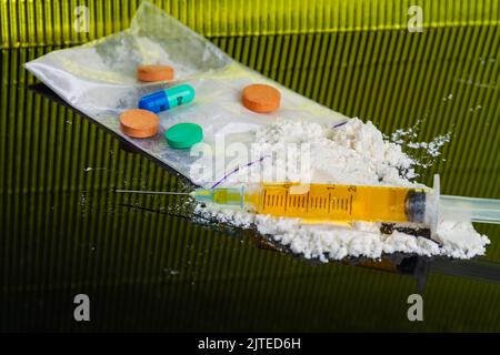 Bunte Tabletten und Pillen mit Spritze und Kokainpulver. Viele verschiedene Drogen. Stockfoto