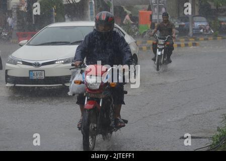 Lahore, Pakistan. 29. August 2022. Pakistanische Menschen auf dem Weg und beschäftigt in Badami bagh Gemüsemarkt während der starken Monsunregen in Lahore. Fourt Bann des Monsunregens hat einen 20-Jahres-Rekord gebrochen, als die Provinzhauptstadt 248mm von Niederschlägen in acht Stunden erhielt. Mindestens fünf Menschen starben und viele wurden verletzt, nachdem zwei Dach- und Mauereinstürze und andere Vorfälle in der Provinzhauptstadt Lahore einstürzten. (Foto von Rana Sajid Hussain/Pacific Press) Quelle: Pacific Press Media Production Corp./Alamy Live News Stockfoto