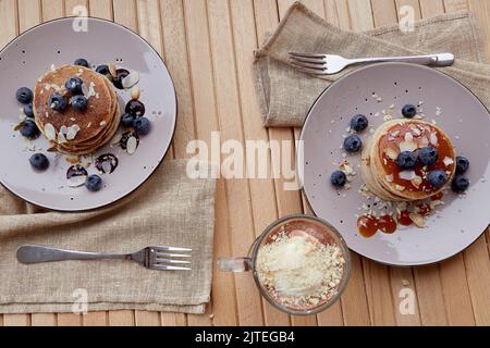 Traditionelle vegane Pfannkuchen mit frischen Heidelbeeren und Agavensirup. Belgische Schokolade mit Eis im Glas. Gesundes Frühstück im Freien. Stockfoto