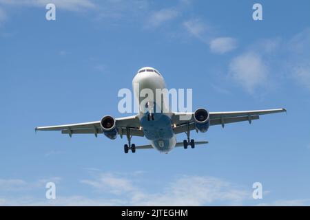 Weißes Passagierflugzeug, das am Himmel mit Wolken im Hintergrund fliegt. Reise- und Flugkonzept Stockfoto