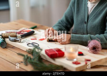 Nahaufnahme der Frau, die zu Hause Weihnachtsgeschenk verpackt Stockfoto