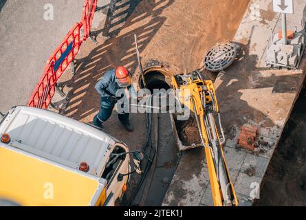 Der Arbeiter führt die Reinigung, Reparatur und Wartung der Straßenabwasserkanäle im Freien durch. Stockfoto
