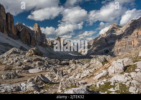 Langes Tal mit vielen weißen Steinen, weiße Wolken am Himmel über hohen Dolomiten-Bergen Stockfoto