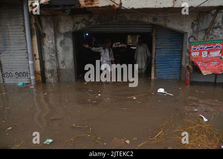 Lahore, Punjab, Pakistan. 29. August 2022. Pakistanische Menschen auf dem Weg und beschäftigt in Badami bagh Gemüsemarkt während der starken Monsunregen in Lahore. Fourt Bann des Monsunregens hat einen 20-Jahres-Rekord gebrochen, als die Provinzhauptstadt 248mm von Niederschlägen in acht Stunden erhielt. Mindestens fünf Menschen starben und viele wurden verletzt, nachdem zwei Dach- und Mauereinstürze und andere Vorfälle in der Provinzhauptstadt Lahore einstürzten. (Bild: © Rana Sajid Hussain/Pacific Press via ZUMA Press Wire) Stockfoto