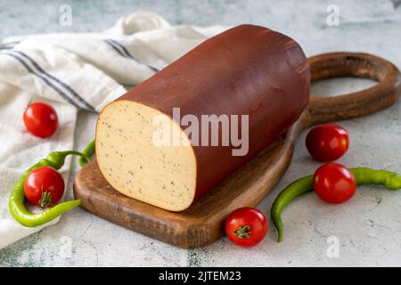 Schwarzer Pfeffer Geräucherter Käse. Holländischer geräucherter Käse auf Steinhintergrund. Nahaufnahme Stockfoto