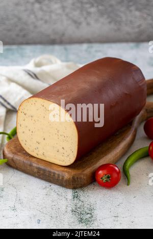 Schwarzer Pfeffer Geräucherter Käse. Holländischer geräucherter Käse auf Steinhintergrund. Nahaufnahme Stockfoto