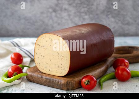 Schwarzer Pfeffer Geräucherter Käse. Holländischer geräucherter Käse auf Steinhintergrund. Nahaufnahme Stockfoto