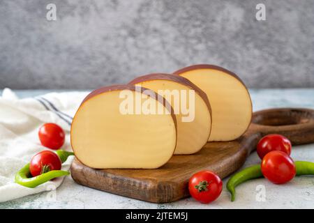 Geräucherter Käse. Holländischer geräucherter Käse auf Steinhintergrund. Nahaufnahme Stockfoto