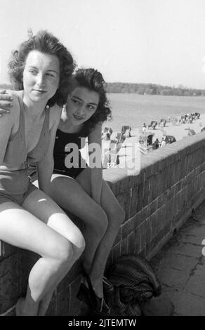 Zwei junge Frauen genießen die Frühlingssonne über Berlin im Schwimmbad Wannsee, Deutschland 1947. Stockfoto