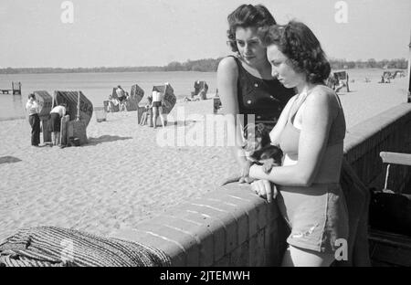 Zwei junge Frauen genießen die Frühlingssonne über Berlin im Schwimmbad Wannsee, Deutschland 1947. Stockfoto