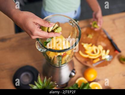 Nahaufnahme der Hände, die Smoothie im Glasmixer Kiwi zubereiten Stockfoto