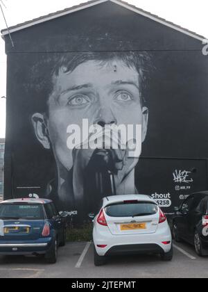 Manchester, England, 19.. Juli 2021 ein Bild von Ian Curtis, Sänger der legendären Manchester-Band Joy Division. Das Bild wurde im August 2022 mit einer Werbung für ein neues Album von einem Rap-Künstler namens „Aitch“ alias Harrisons James Armstrong ©GED Noonan/Alamy übermalt Stockfoto