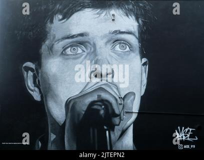 Manchester, England, 19.. Juli 2021 ein Bild von Ian Curtis, Sänger der legendären Manchester-Band Joy Division. Das Bild wurde im August 2022 mit einer Werbung für ein neues Album von einem Rap-Künstler namens „Aitch“ alias Harrison James Armstrong übermalt. Das Wandbild wurde von Akse ©GED Noonan/Alamy geschaffen Stockfoto