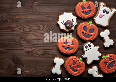 Halloween Lebkuchen - Kürbisse, Geister, Spinne und Knochen auf einem hölzernen Hintergrund. Draufsicht. Platz für eine Inschrift. Stockfoto