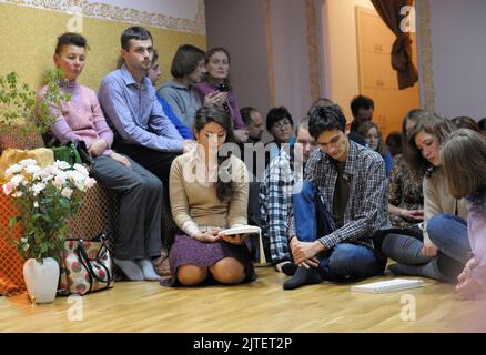 Krishna-Gemeindemitglieder sitzen auf einem Boden und lesen Mantra aus dem Buch. 3. April 2013. Kiew, Ukraine Stockfoto