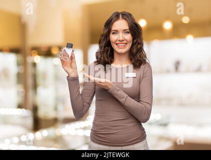 Glückliche weibliche Verkäuferin mit Parfüm Stockfoto