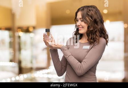 Glückliche weibliche Verkäuferin mit Parfüm Stockfoto