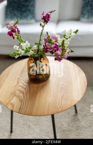 Blumen in Vase auf runden Couchtisch zu Hause Stockfoto