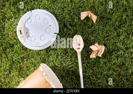 Nahaufnahme der gebrauchten Einweg-Kaffeetasse auf Gras Stockfoto