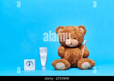 teddybär mit Zahnbürste, Zahnpasta und Uhr Stockfoto