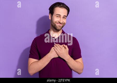 Foto von niedlichen Millennial Brunet Kerl Palmen Brust tragen violette T-Shirt isoliert auf lila Farbe Hintergrund Stockfoto