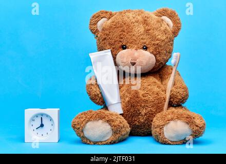 teddybär mit Zahnbürste, Zahnpasta und Uhr Stockfoto