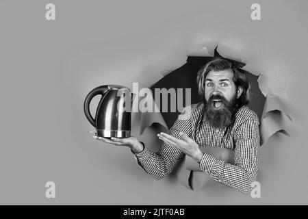 Kerl mit Bart trinken Tee. Brutal kaukasischen Hipster mit Wasserkocher. Trinken Sie heißes Getränk. Gute Qualität. Überrascht Shop-Assistent. Reifer Mann Stockfoto