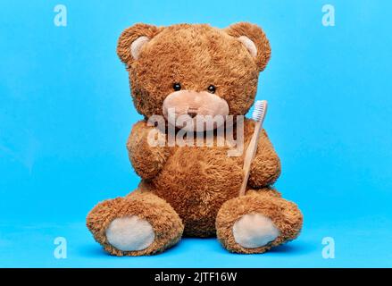 teddybär Spielzeug mit Zahnbürste auf blauem Hintergrund Stockfoto